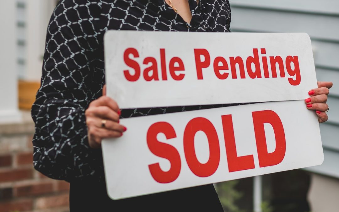 woman holding house sale and sold signs