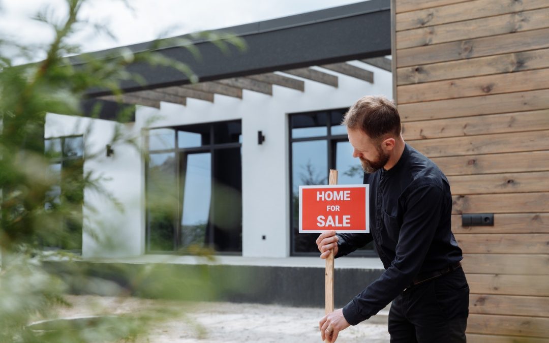 man placing home for sale sign