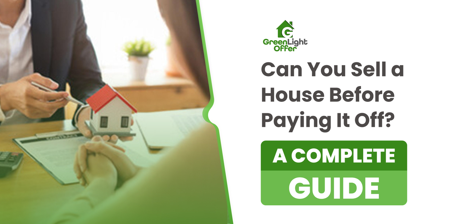Hands discussing a miniature house model and paperwork, with text overlay "Can You Sell a House Before Paying It Off? A Complete Guide" and Greenlight Offer logo, representing real estate selling guidance.